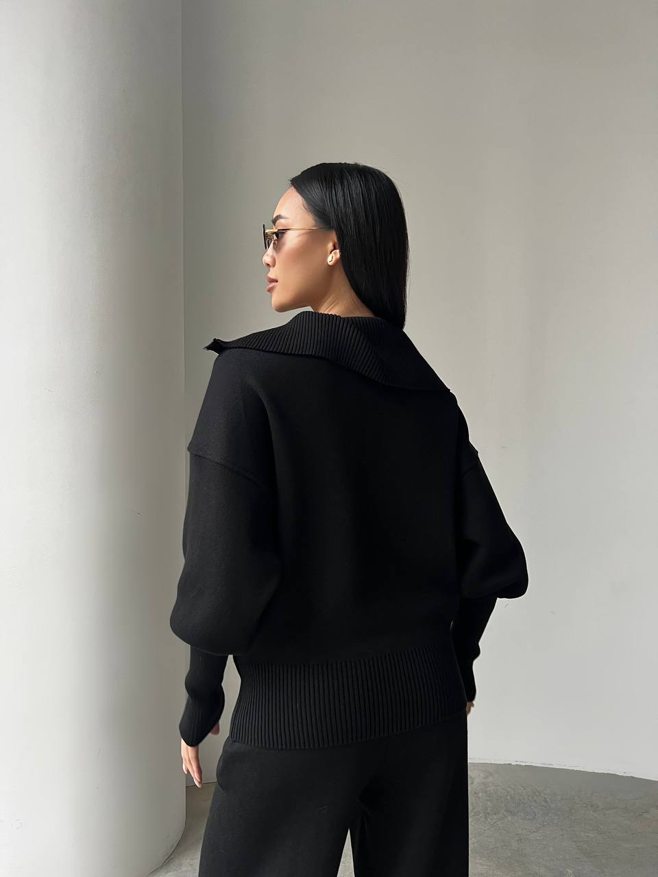 Person wearing a black outfit against a plain background