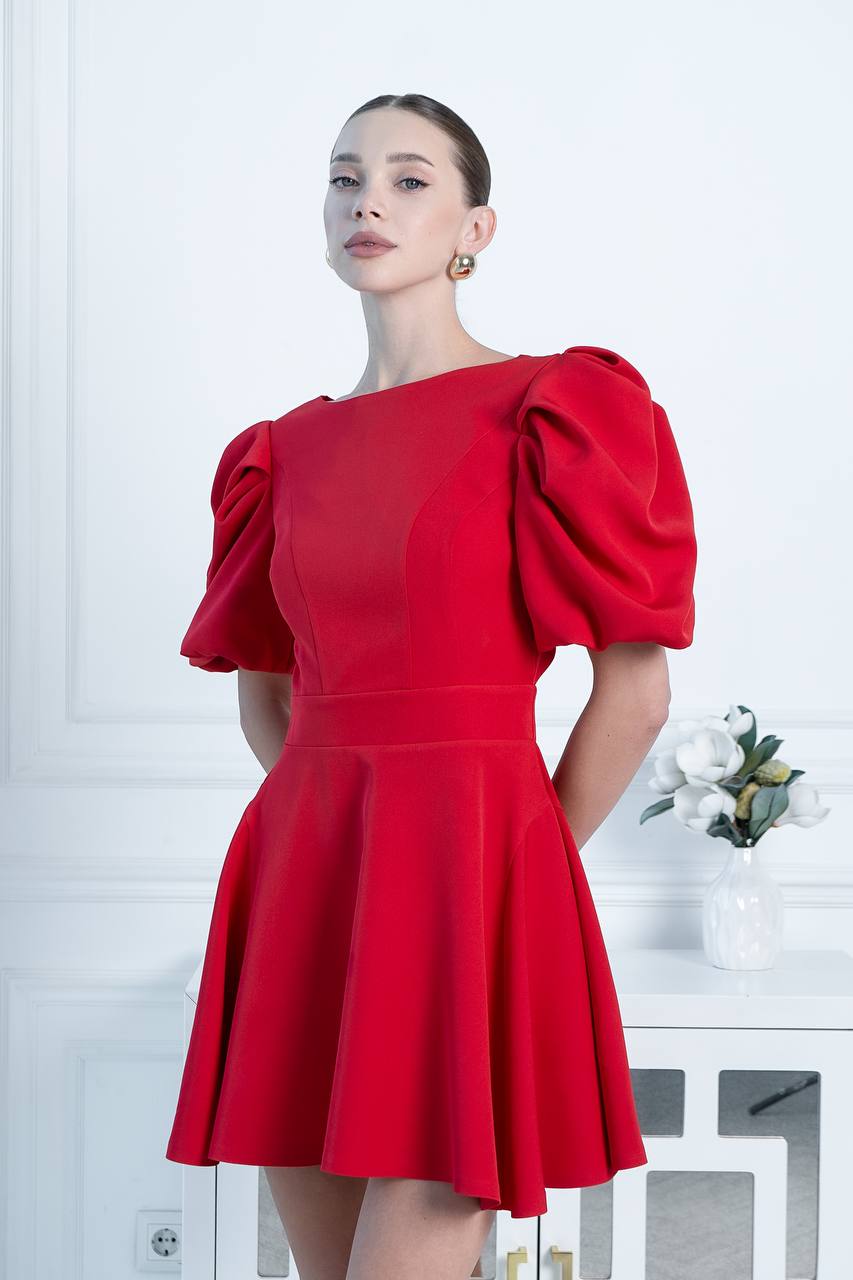 Woman wearing a red dress with puff sleeves against a white background