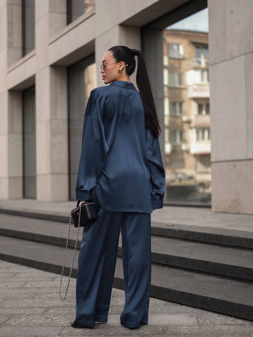 Woman in a blue outfit standing on steps with a building in the background