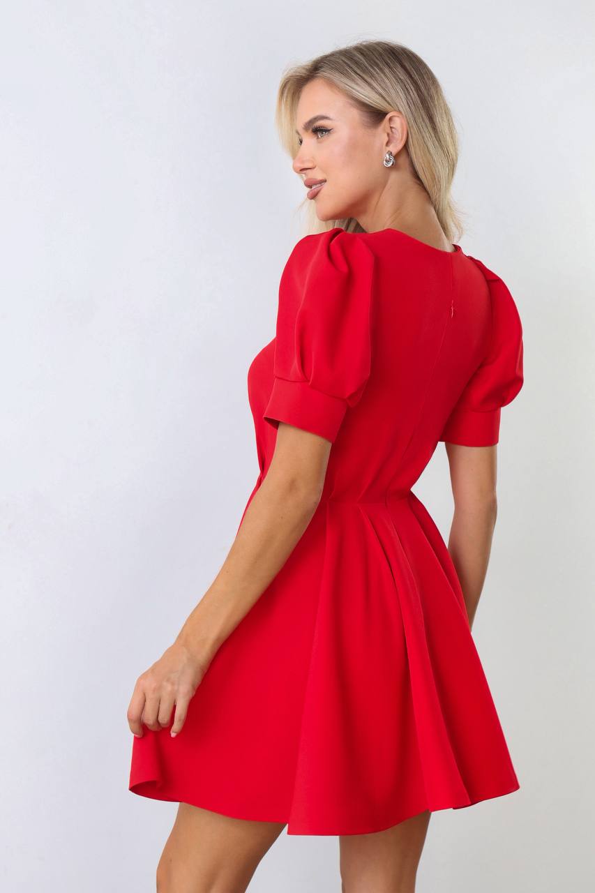Woman wearing a red dress with puff sleeves against a white background