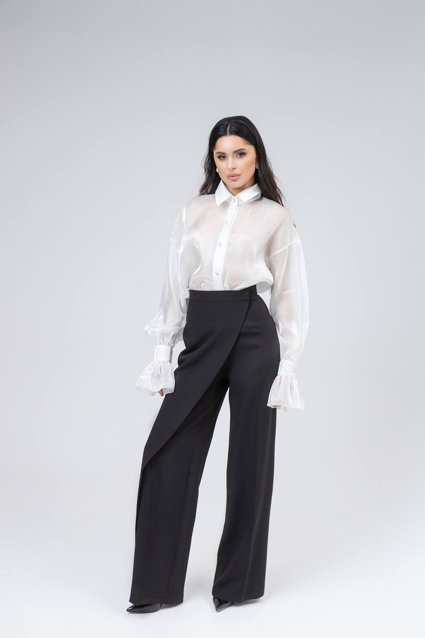 Woman wearing a white blouse and black pants on a white background