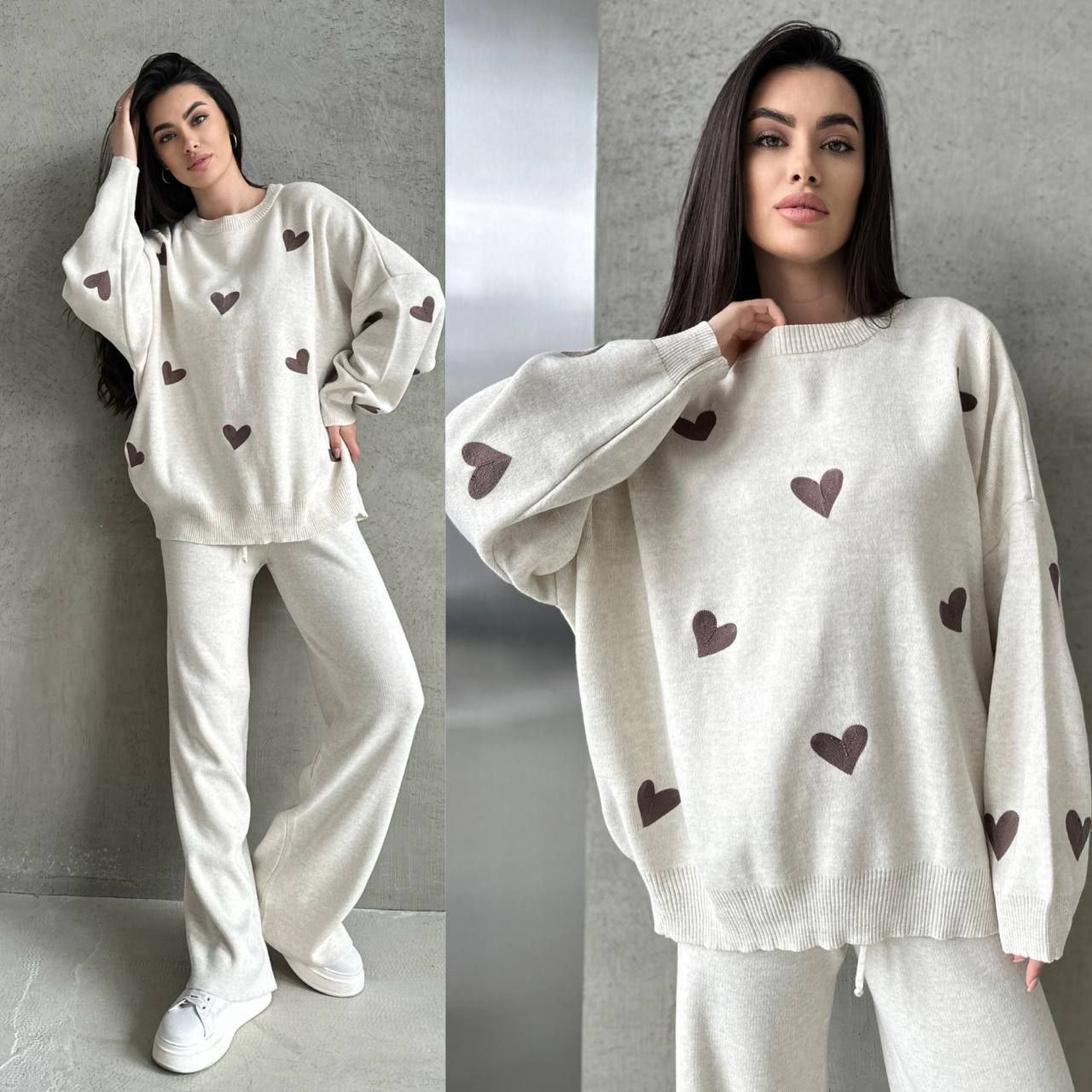 Woman wearing a white sweater and pants with heart patterns against a gray background