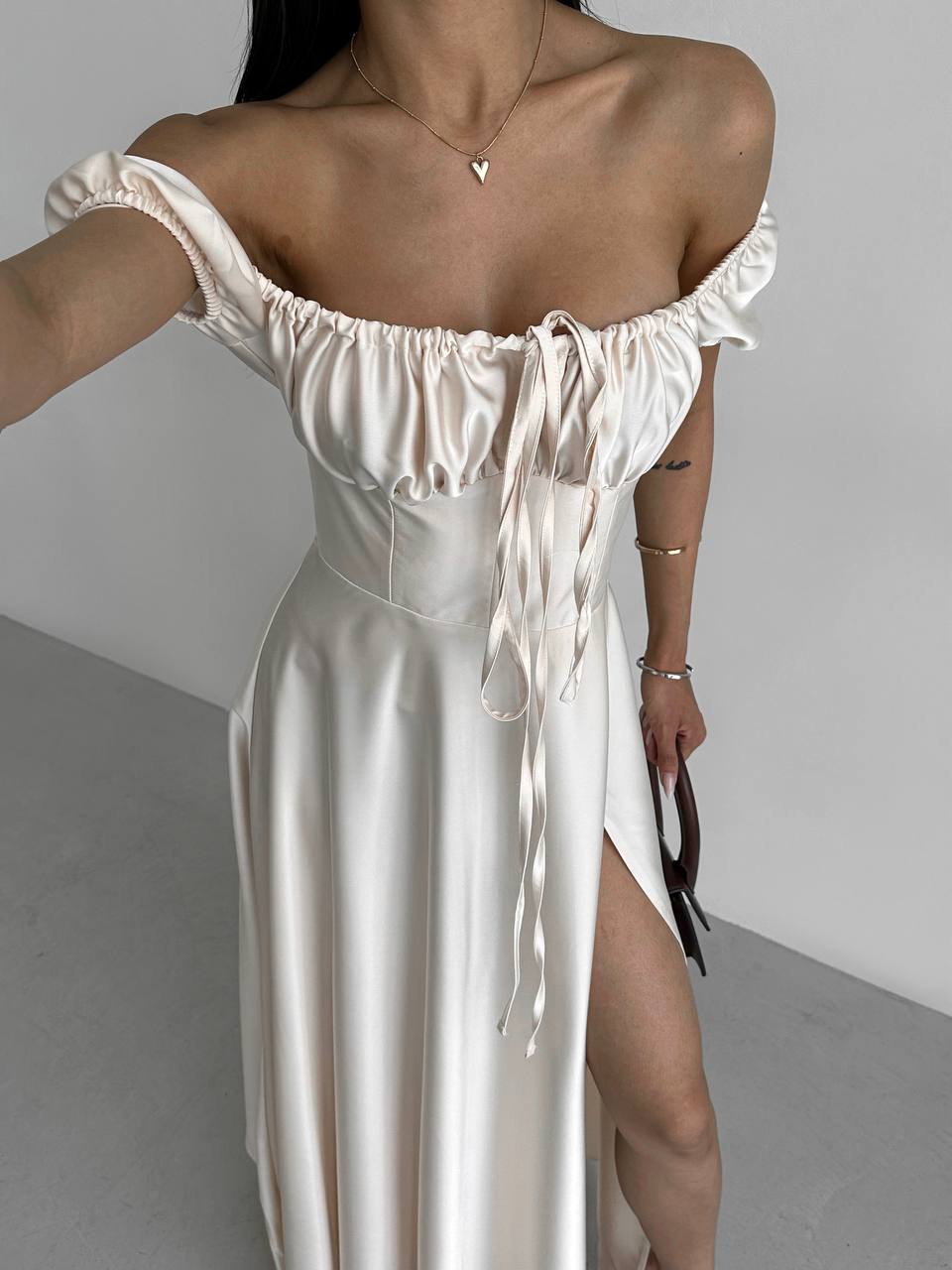 White off-shoulder dress with a high slit on a plain background