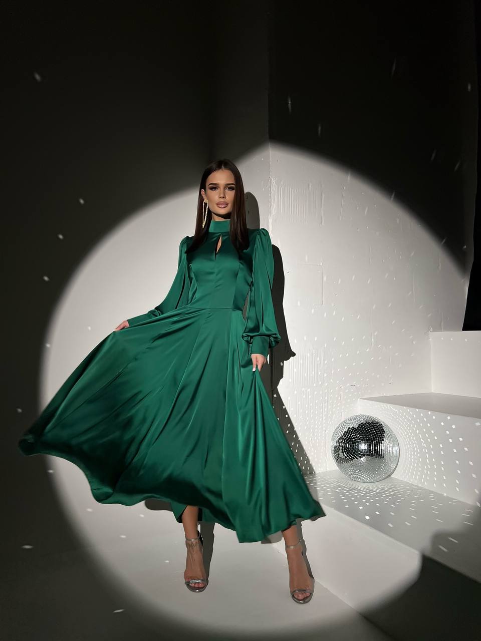 Woman in a green dress standing on a stage with a spotlight