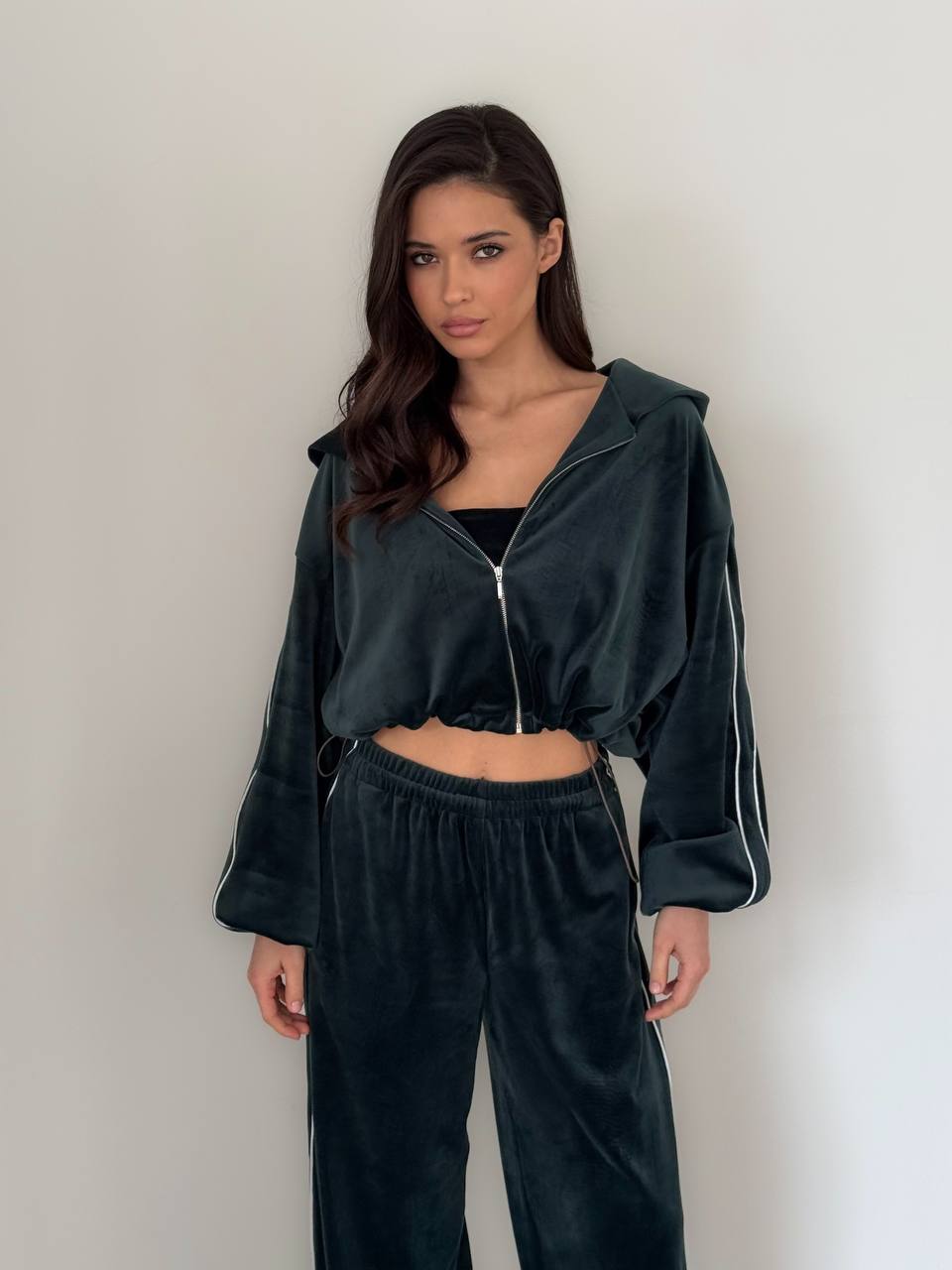 Woman wearing a dark green tracksuit against a plain background