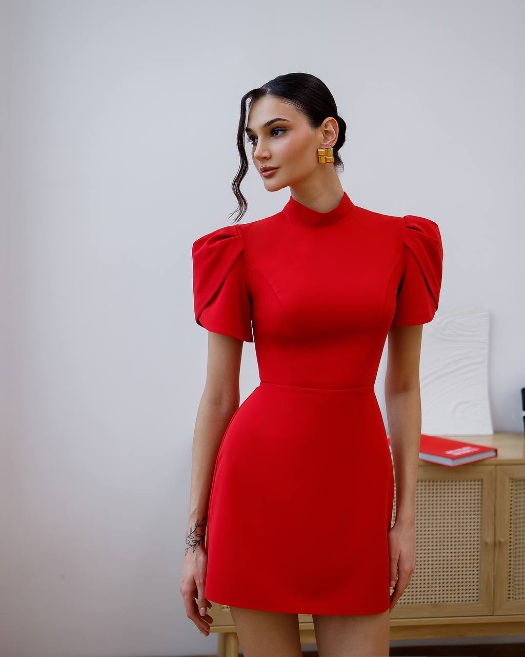 Woman wearing a red dress with puff sleeves against a plain background