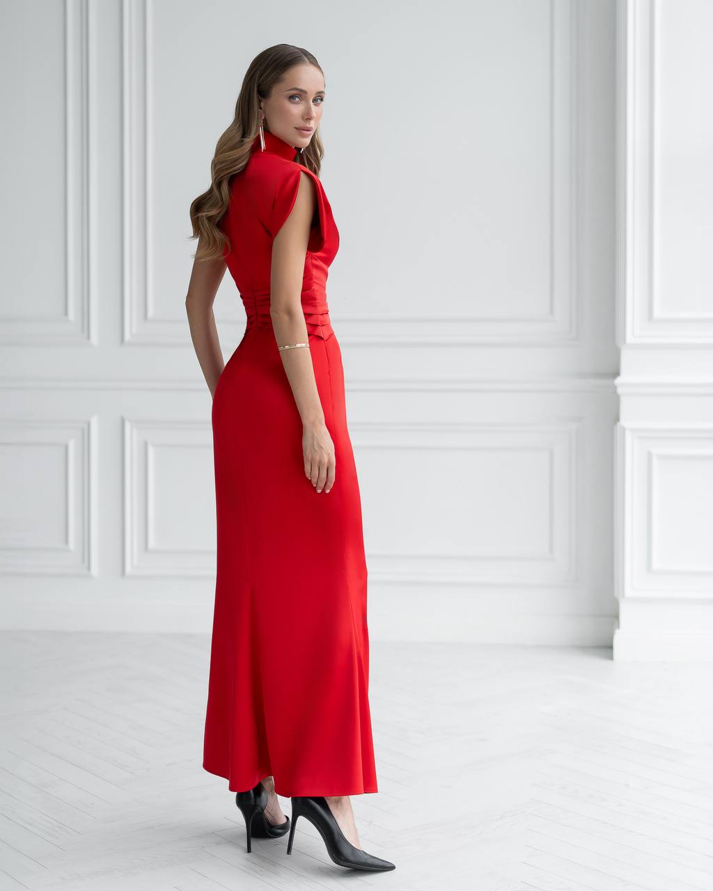 Woman wearing a red dress against a white paneled wall