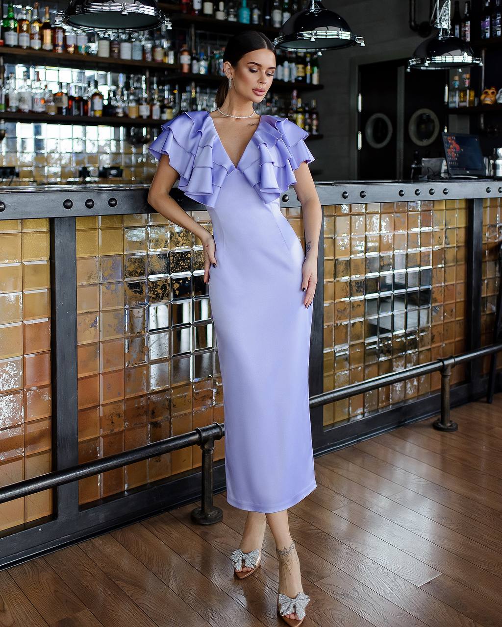 Woman in a lavender dress standing in a bar setting