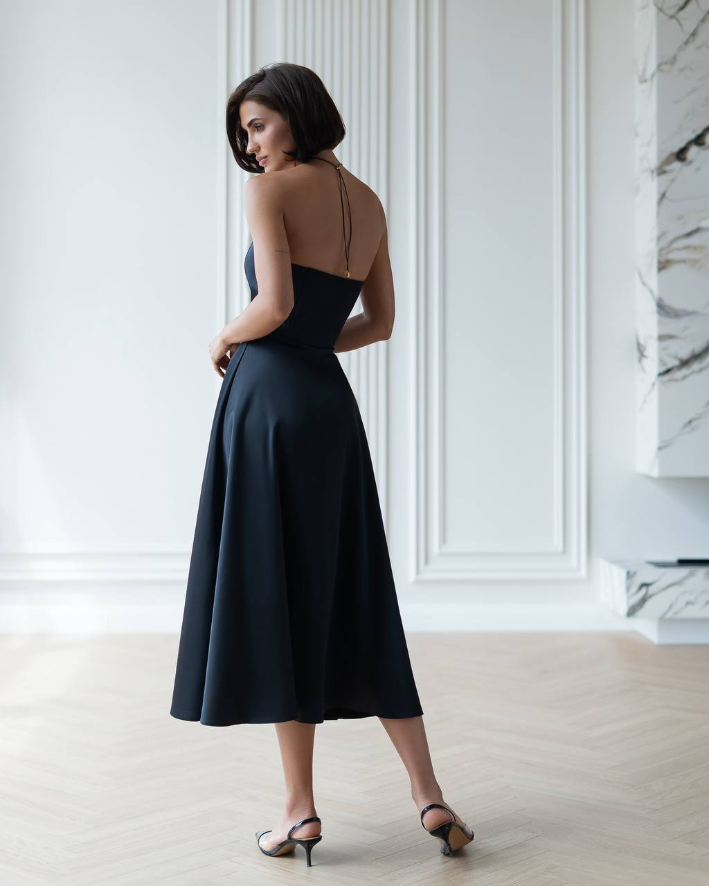 Woman wearing a black dress with a backless design in an elegant room.