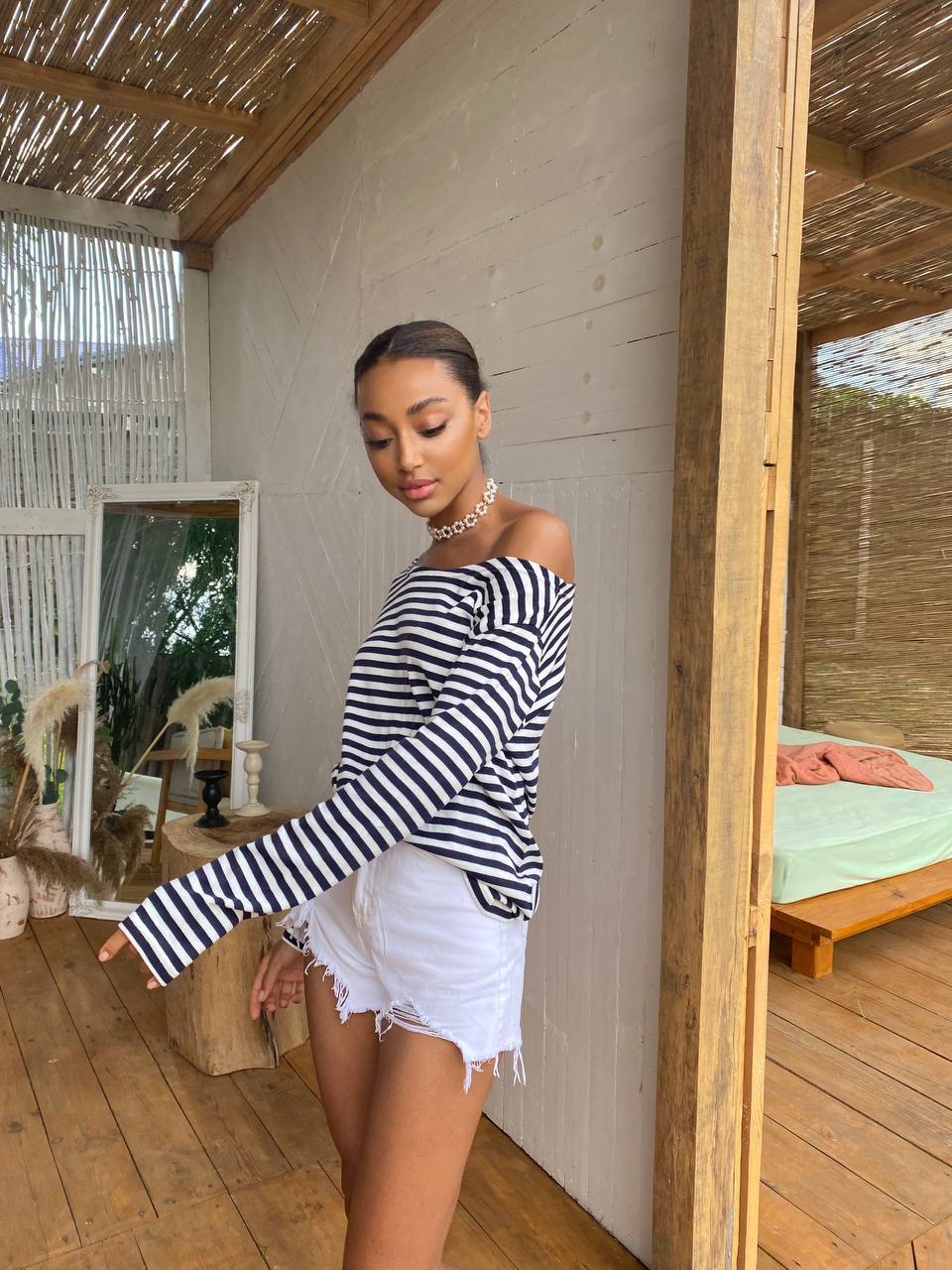Woman wearing a black and white striped shirt and white shorts in a rustic wooden cabin.