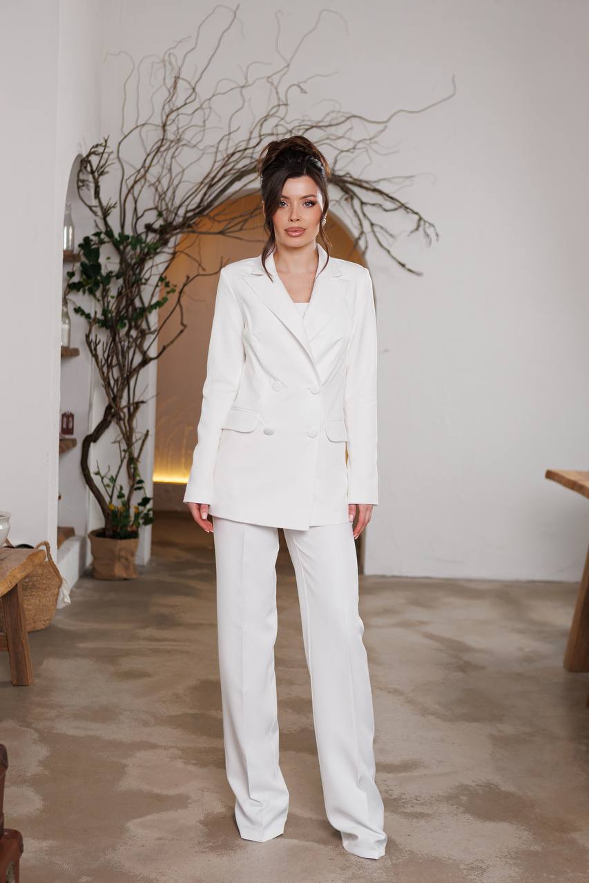 Woman in a white suit standing in a room with minimal decor