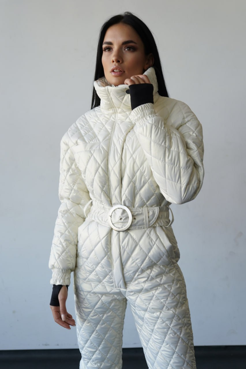 Woman wearing a white quilted snowsuit against a plain background