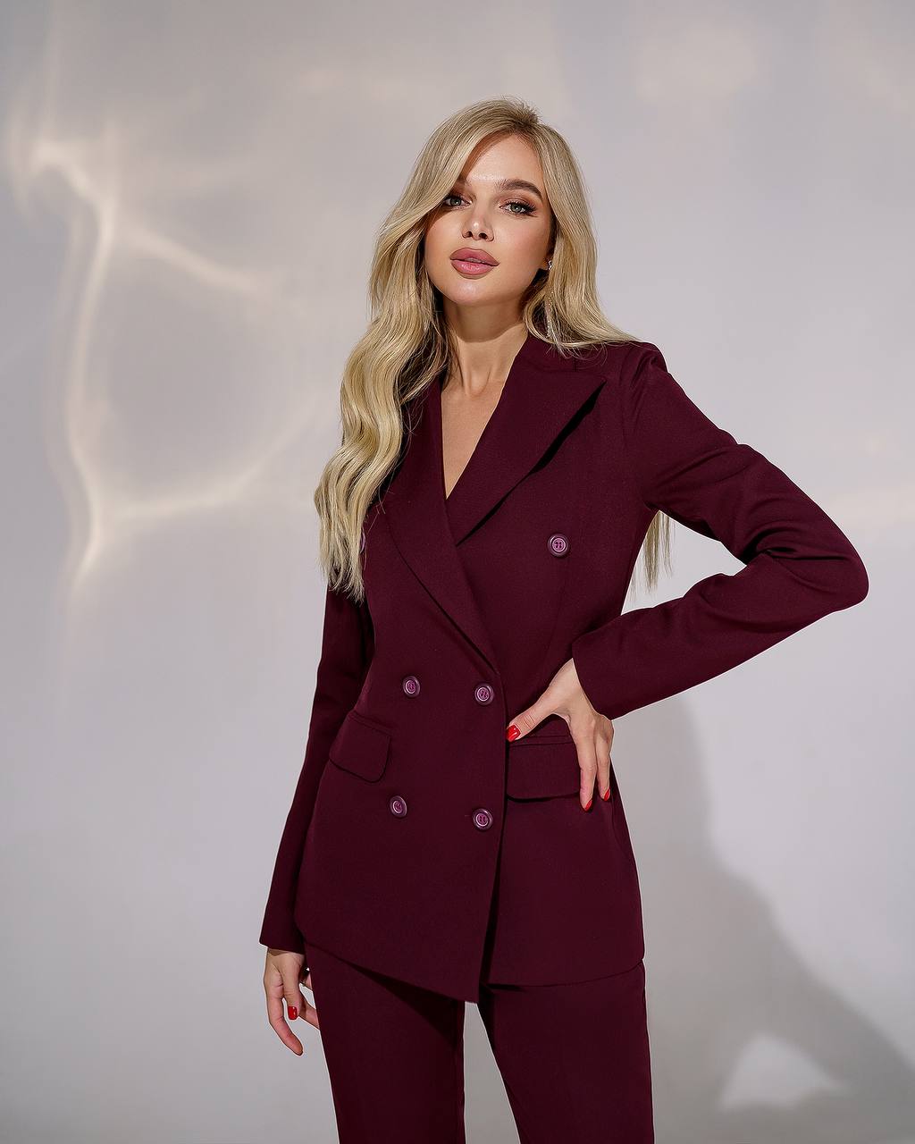 Woman wearing a burgundy suit against a plain background