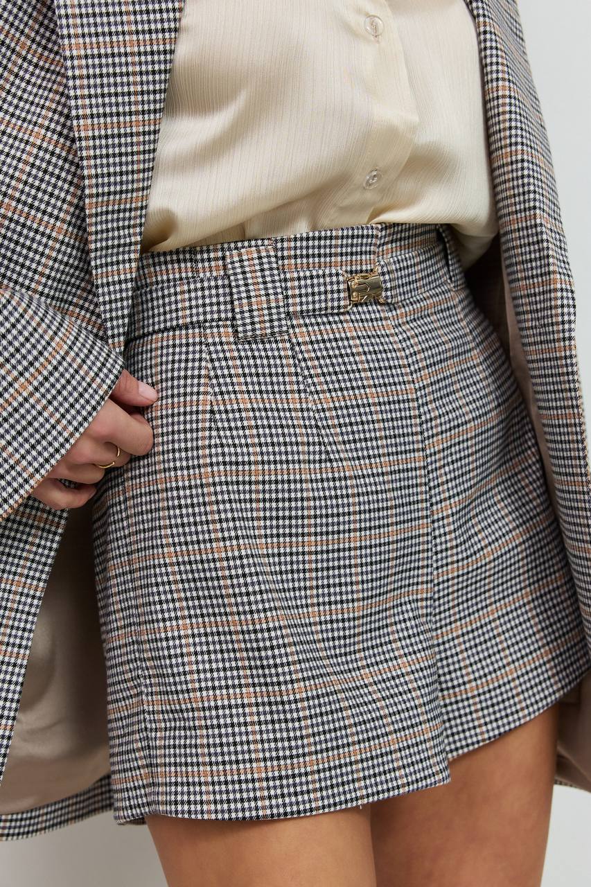 Person wearing a plaid skirt with a matching blazer and shirt.