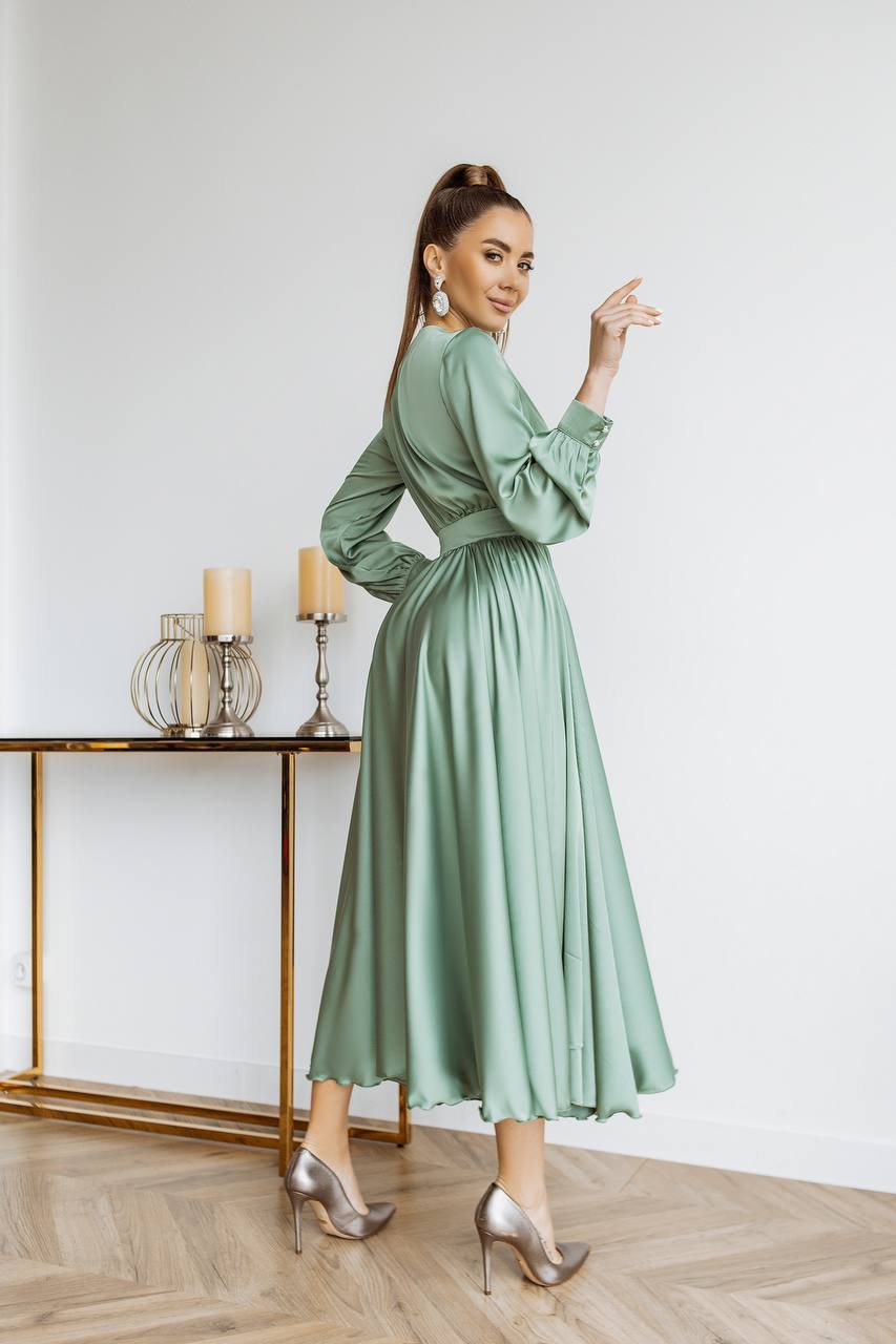Woman in a green dress standing in a room with a table and candles.