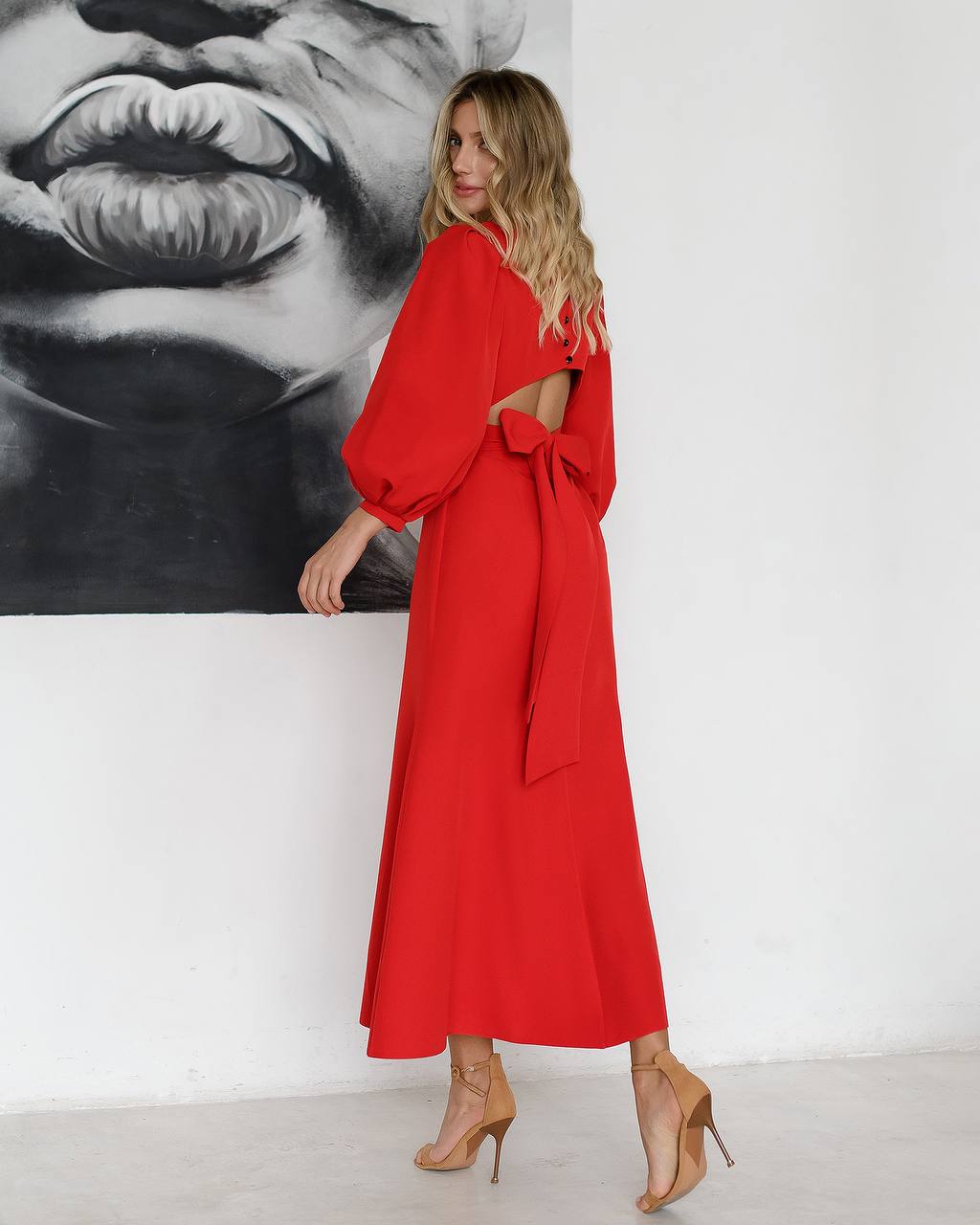 Woman in a red dress standing in front of a black and white painting.