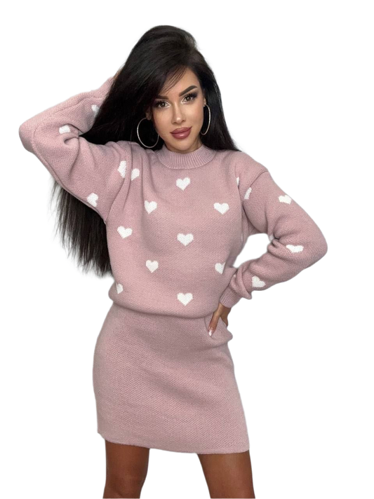 Woman wearing a pink sweater with heart patterns and a matching skirt on a white background