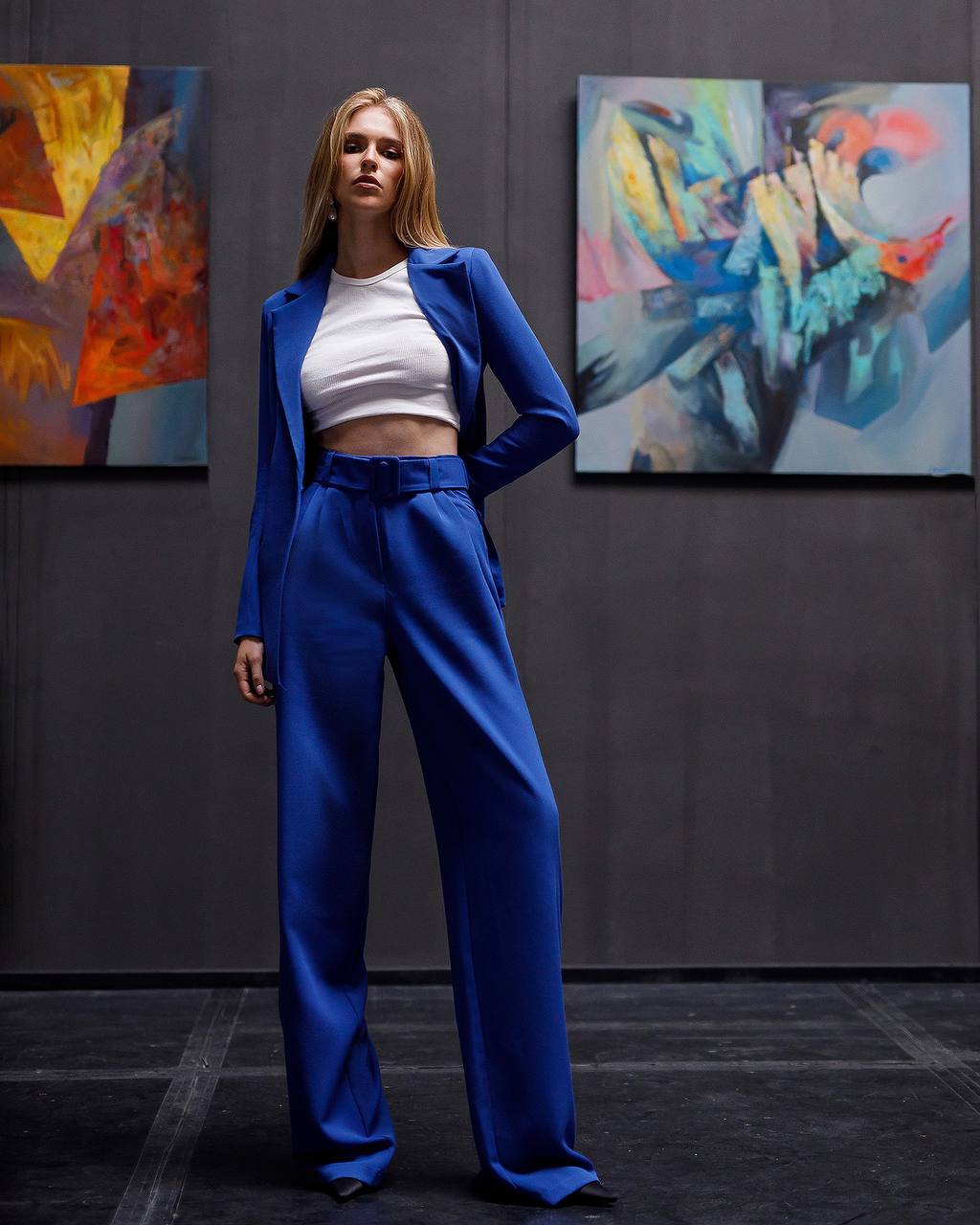Woman in a blue outfit standing in front of abstract paintings