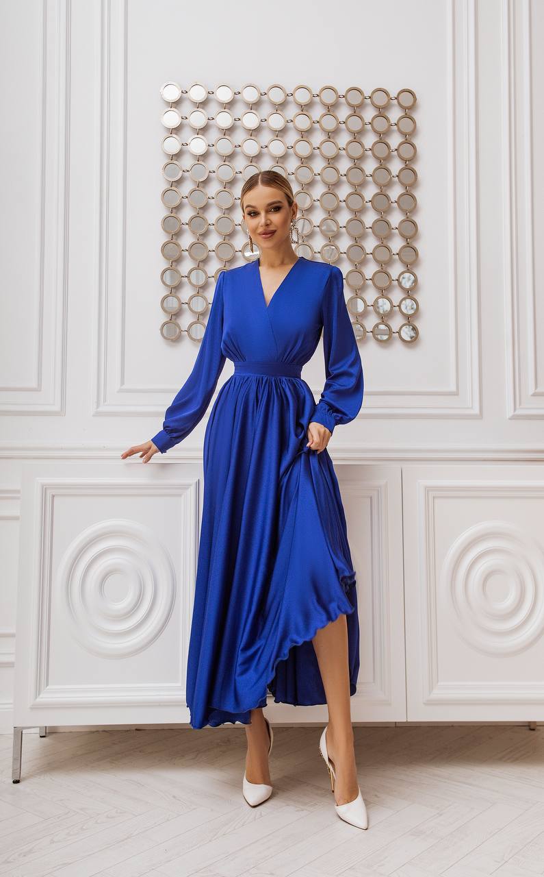 Woman wearing a blue dress standing in front of decorative wall panels.