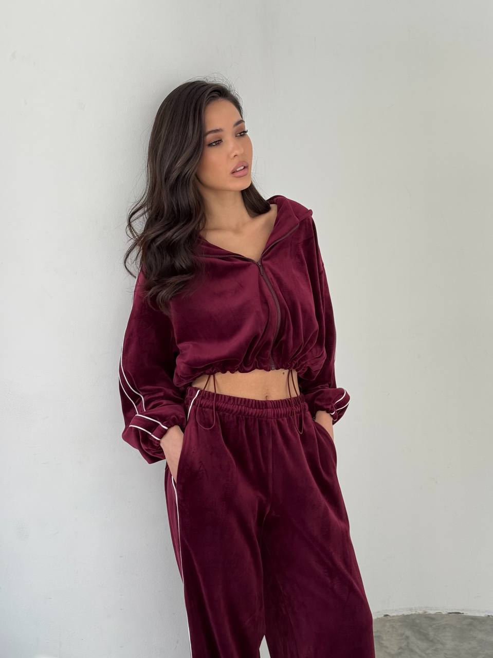 Woman wearing a burgundy tracksuit against a plain background