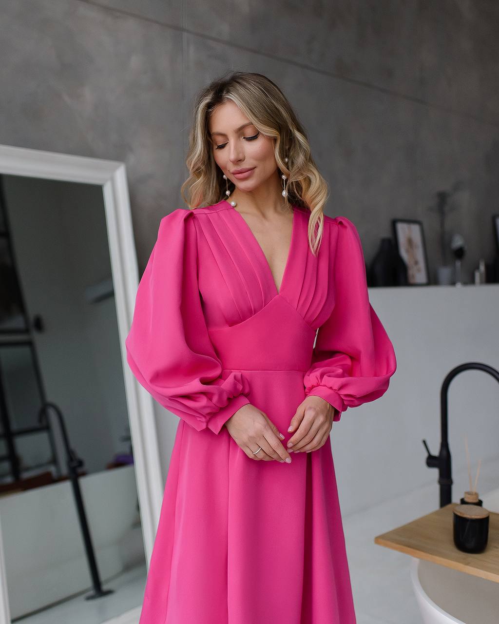 Woman wearing a bright pink dress with puffed sleeves in an indoor setting.