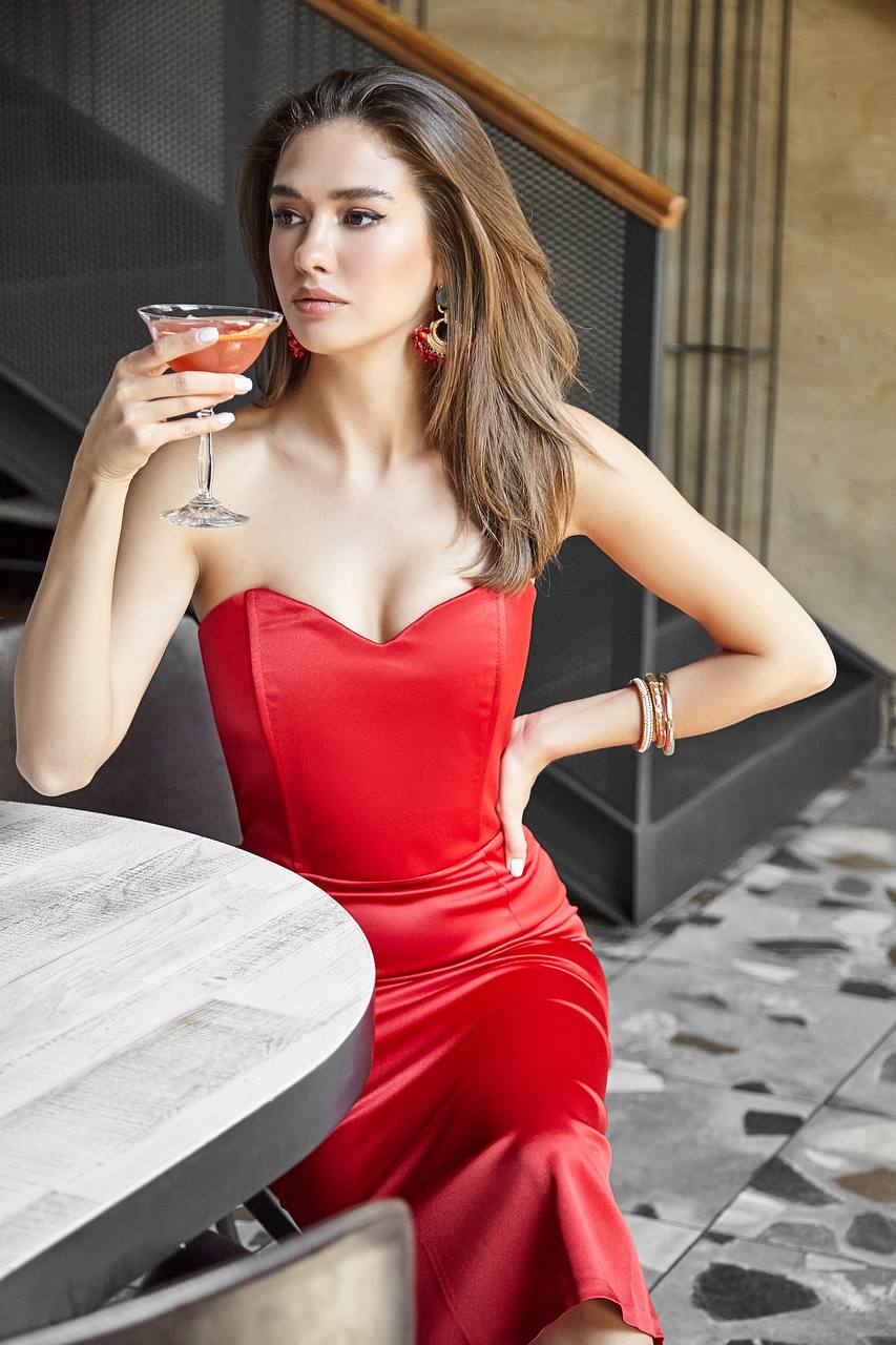 Woman in a red dress holding a cocktail at an outdoor setting