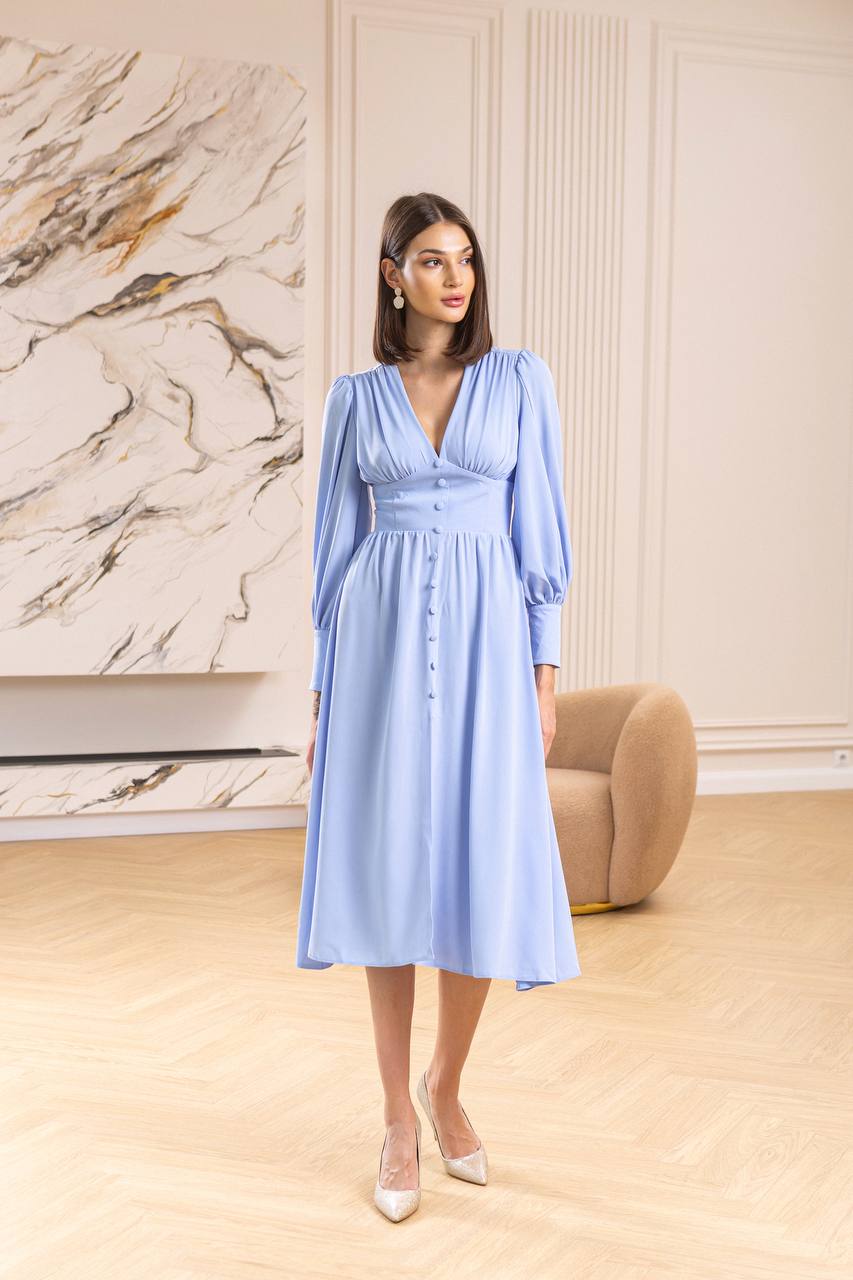 Woman wearing a light blue dress in an elegant room with marble wall.