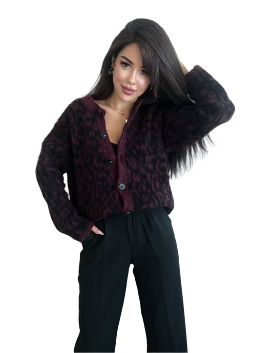 Woman wearing a dark patterned cardigan over a black top with black pants on a white background