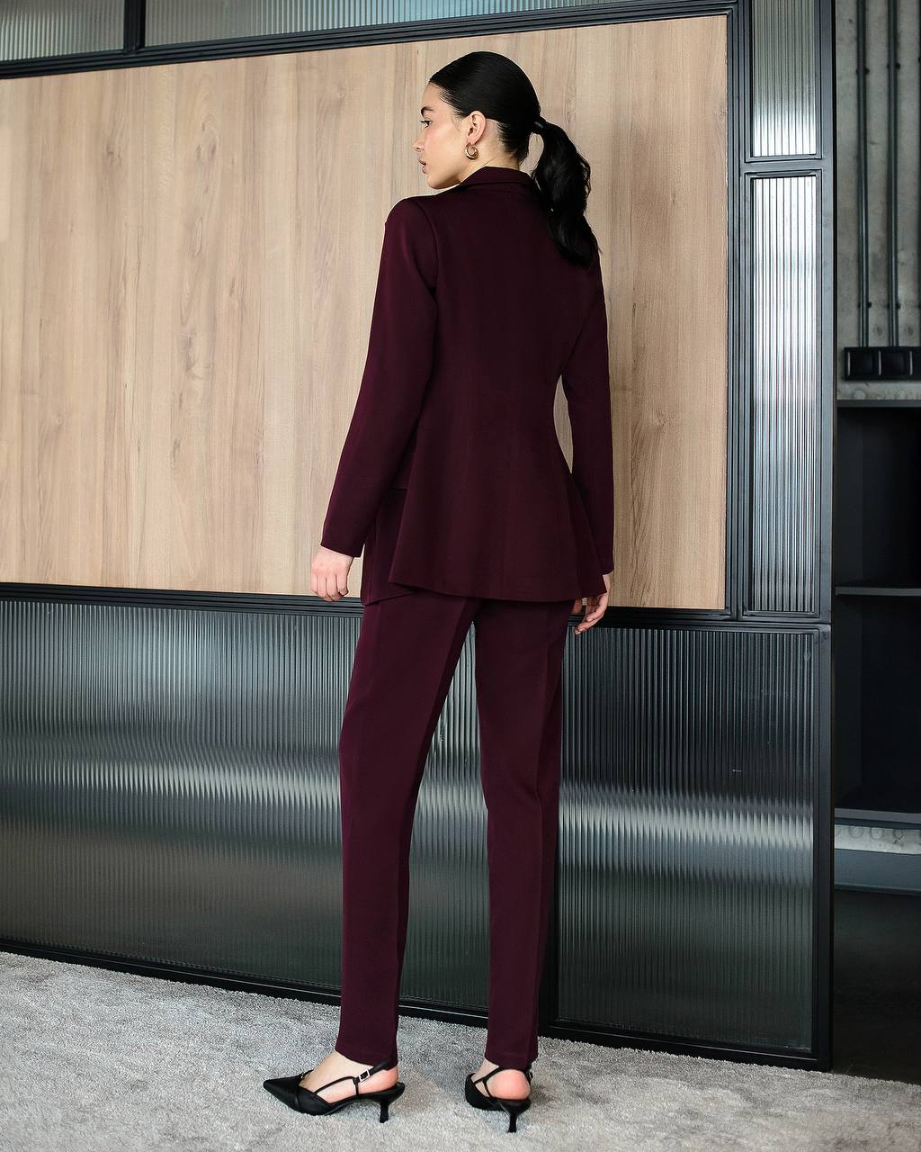 Woman wearing a burgundy suit standing in an office setting.