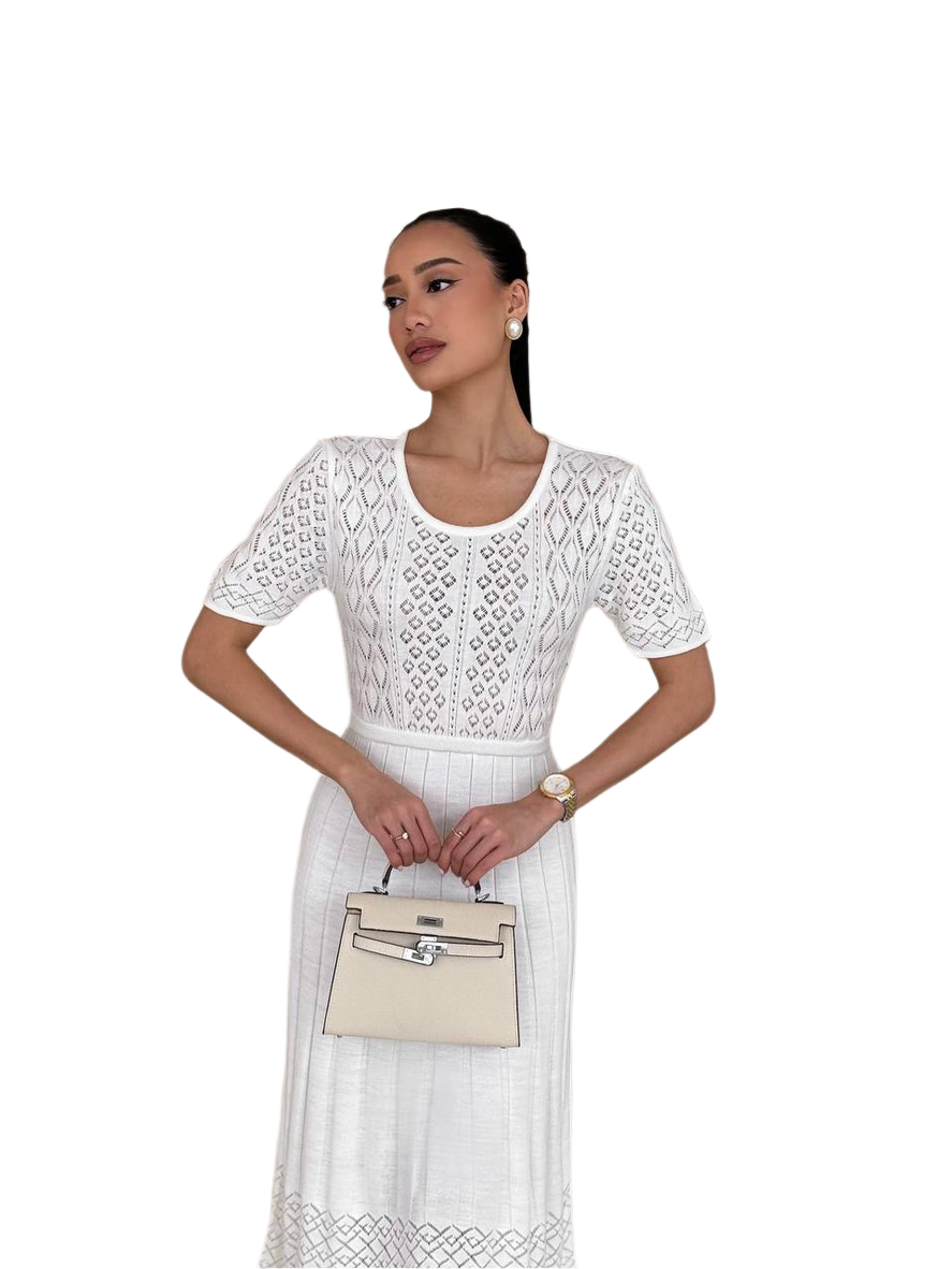 Woman wearing a white lace dress holding a beige handbag on a white background