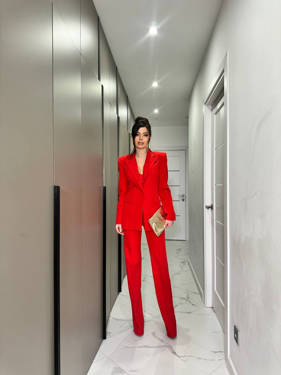 Person in a red suit standing in a modern hallway.