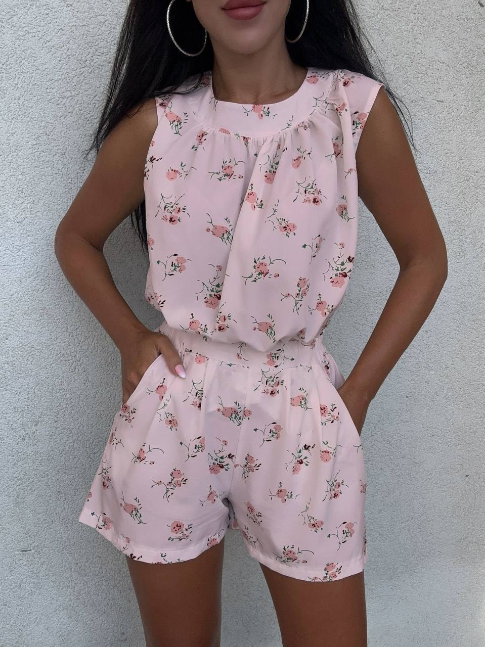 Woman wearing a pink floral romper against a light gray background