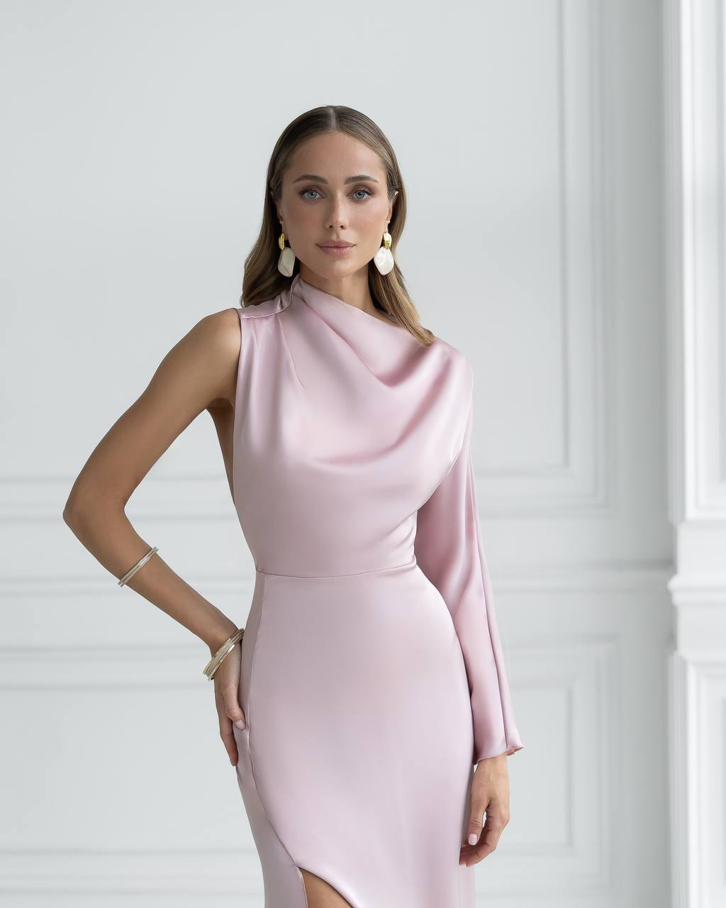 Woman wearing a pink dress against a white wall