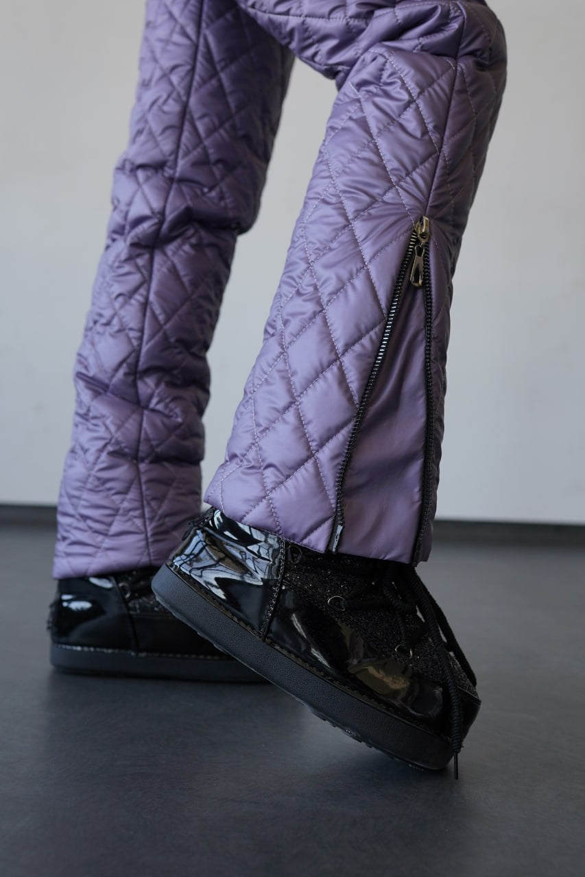 Purple quilted pants and black shoes on a plain background