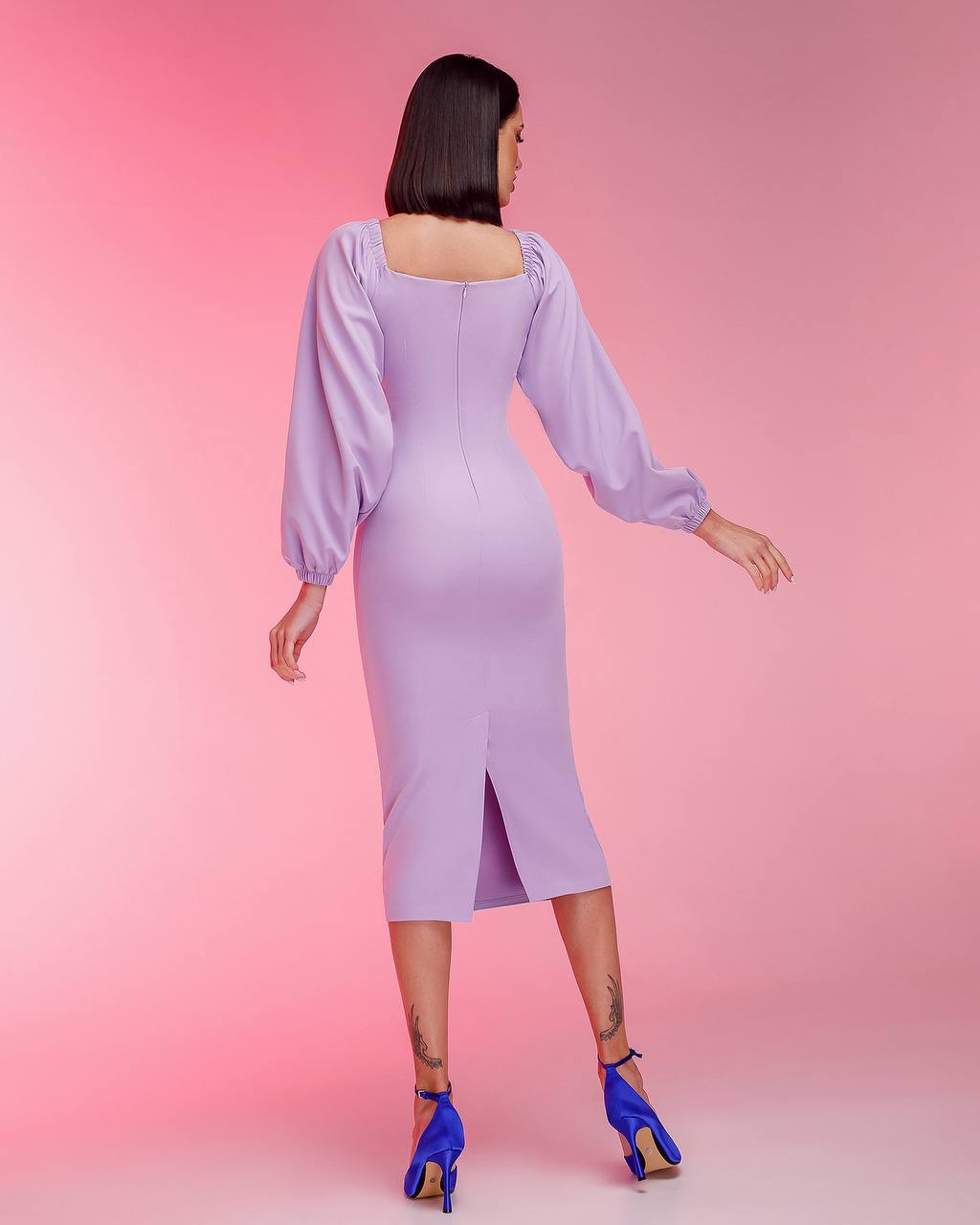 Woman wearing a light purple dress with long sleeves on a pink background