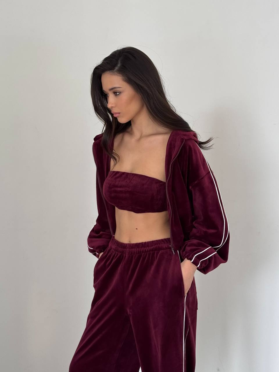 Woman wearing a burgundy tracksuit with a white background