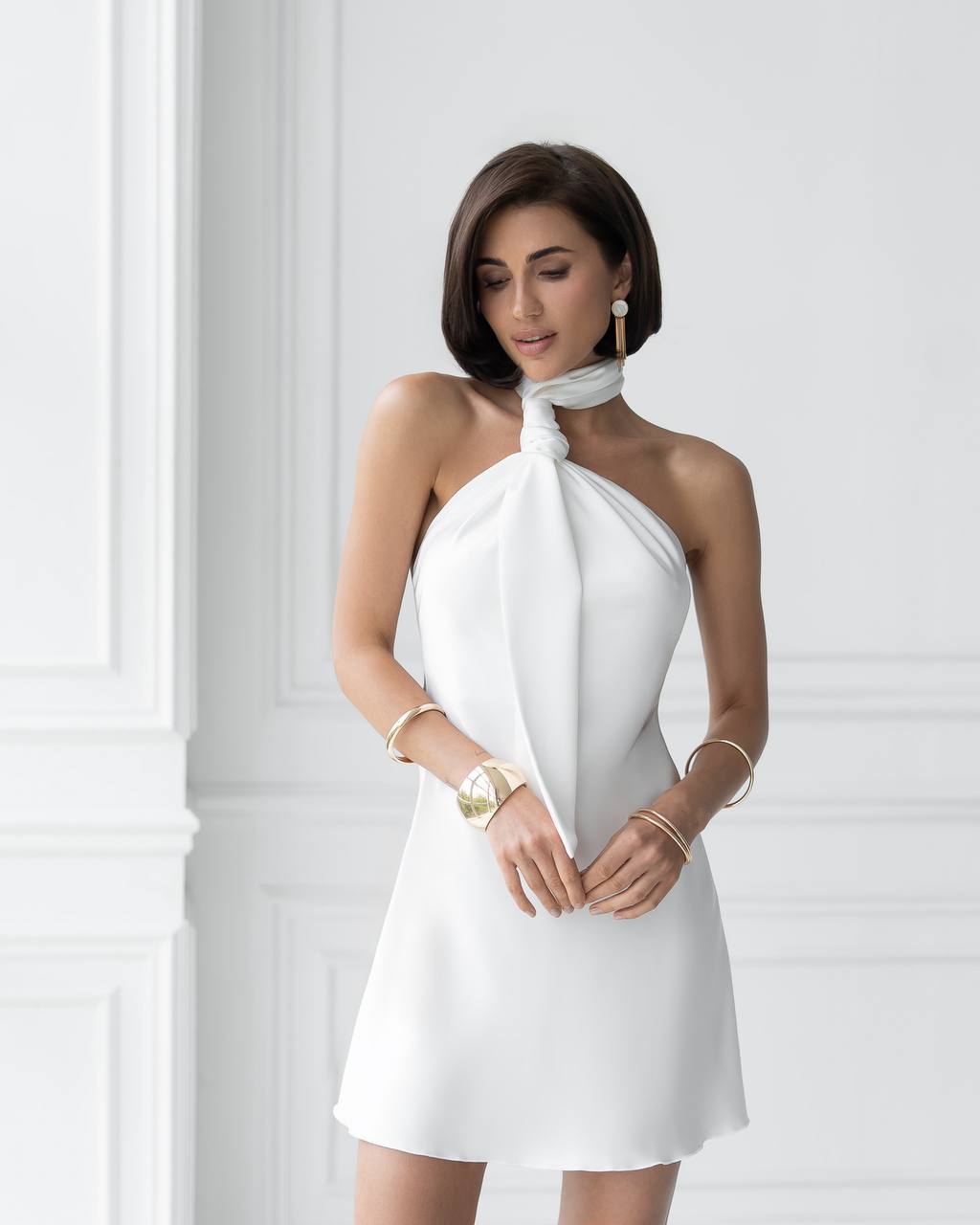 Woman wearing a white one-shoulder dress against a white background