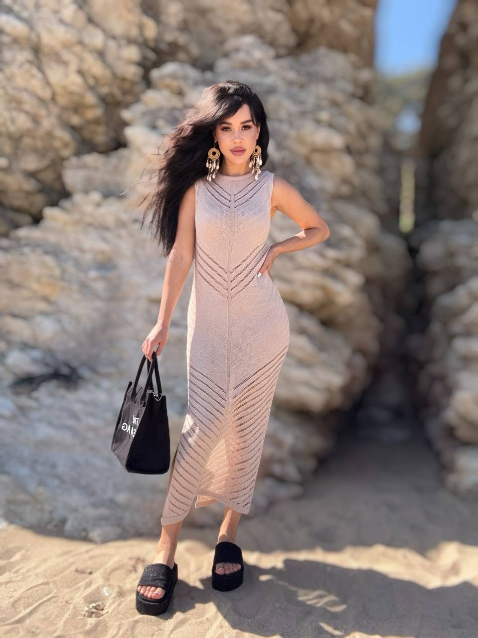 Woman in a patterned dress standing on a rocky beach
