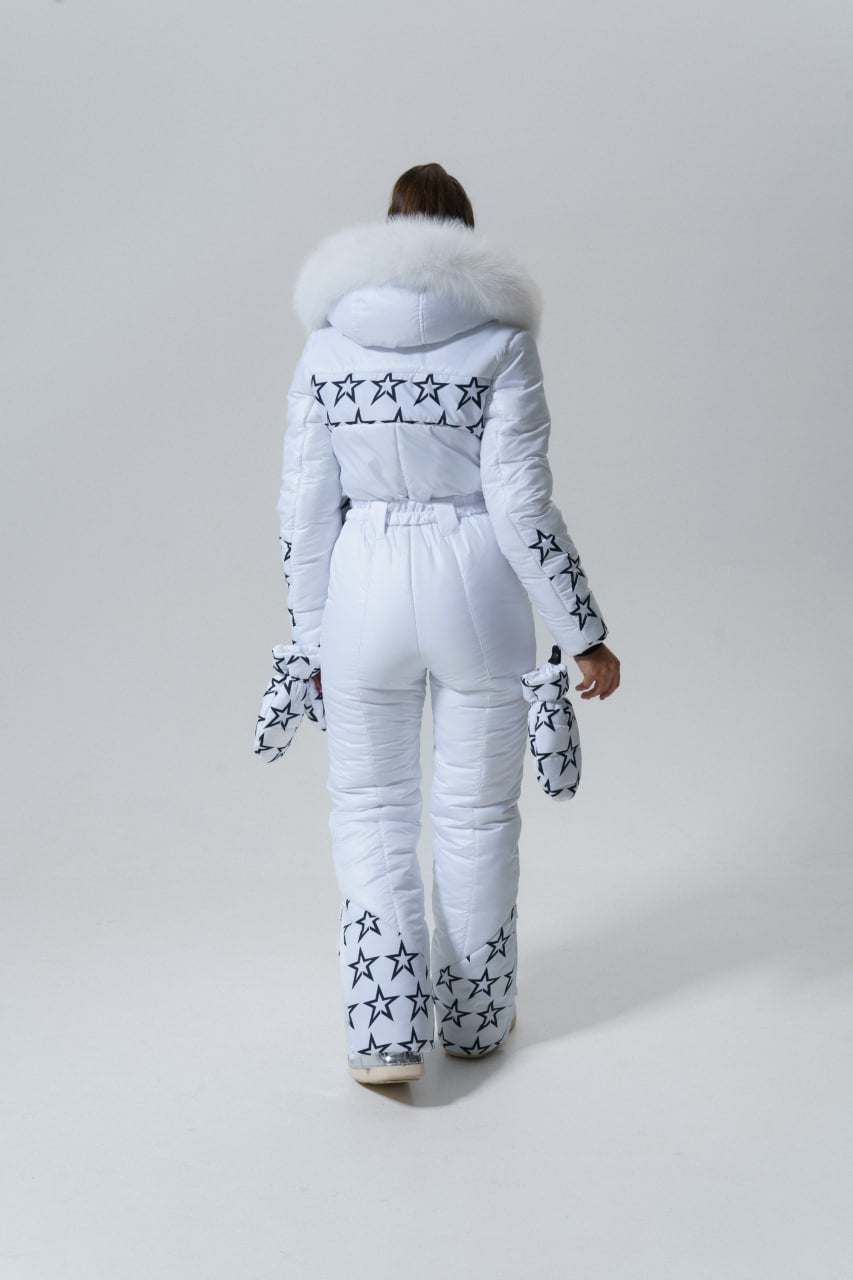 Person wearing a white snowsuit with star patterns on a plain background
