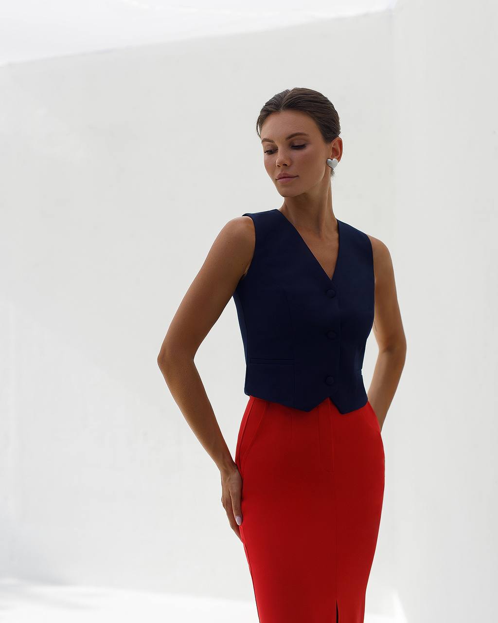 Woman wearing a navy top and red skirt on a white background