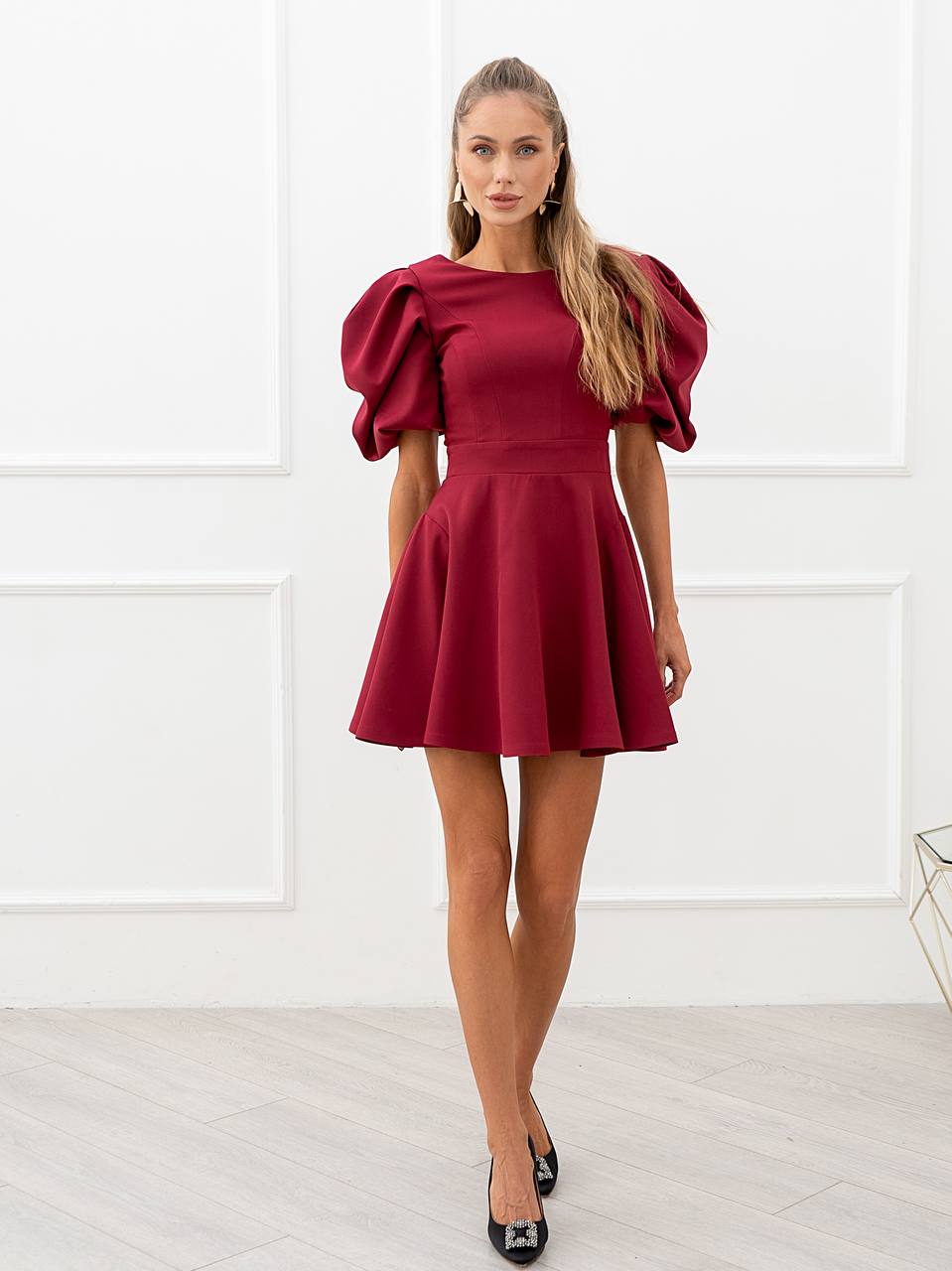 Woman wearing a red dress with puff sleeves against a white background