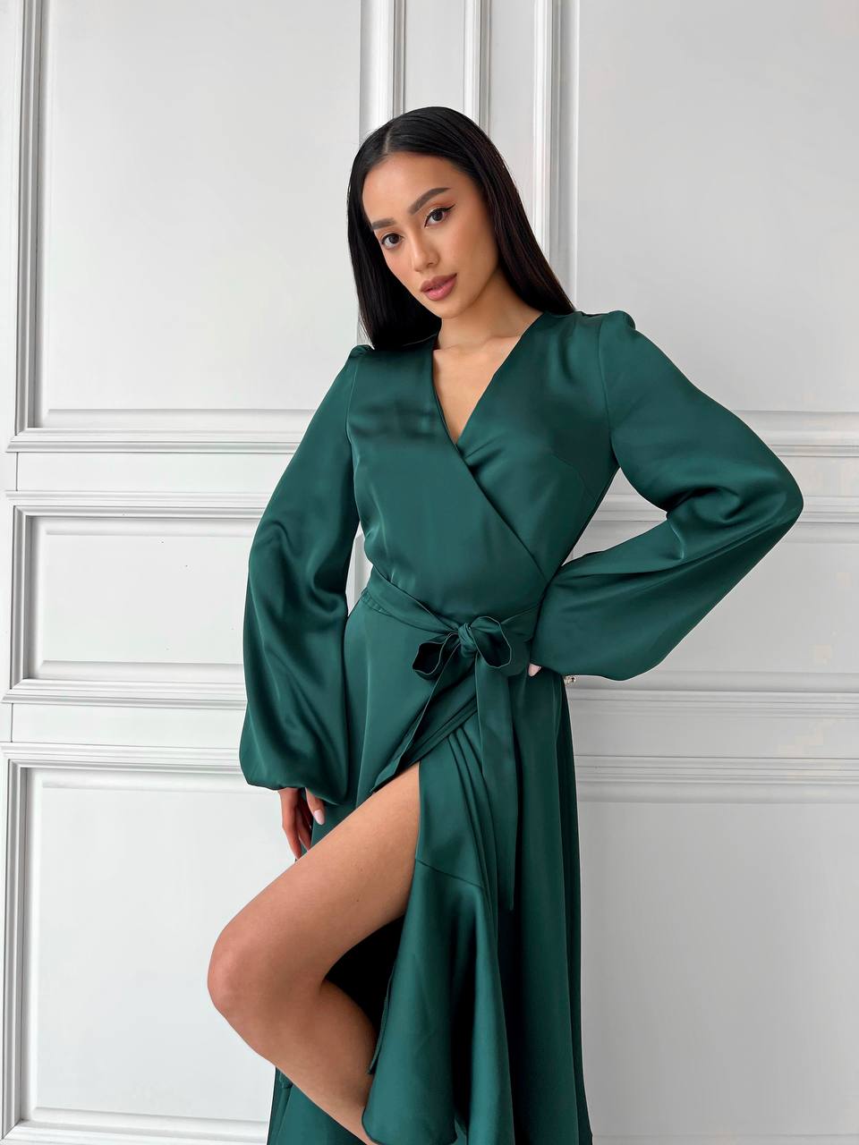 Woman wearing a green satin robe against a white wall