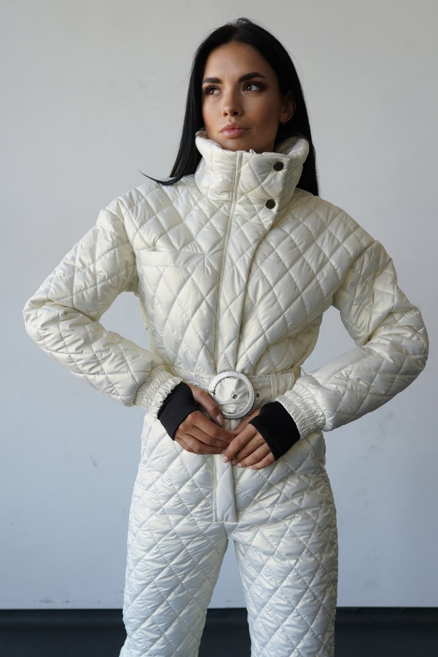 Woman wearing a white quilted jumpsuit against a plain background