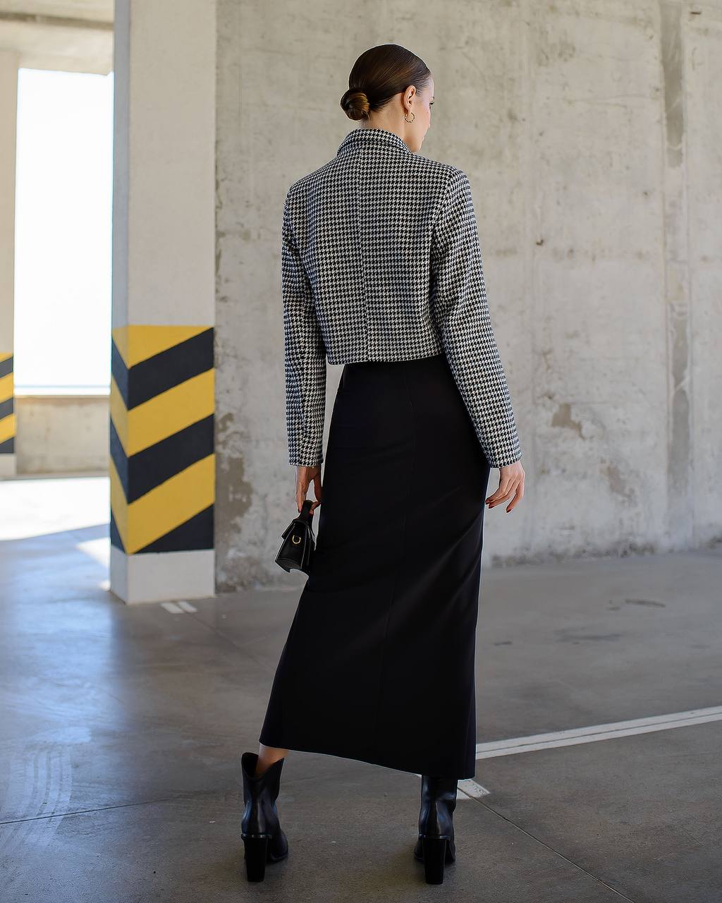 Person wearing a checkered shirt and black skirt in an industrial setting
