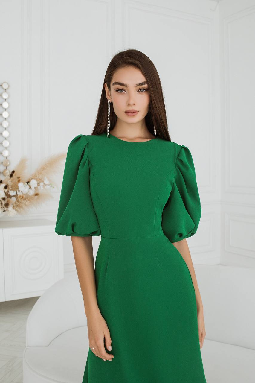 Woman wearing a green dress with puffed sleeves against a white background