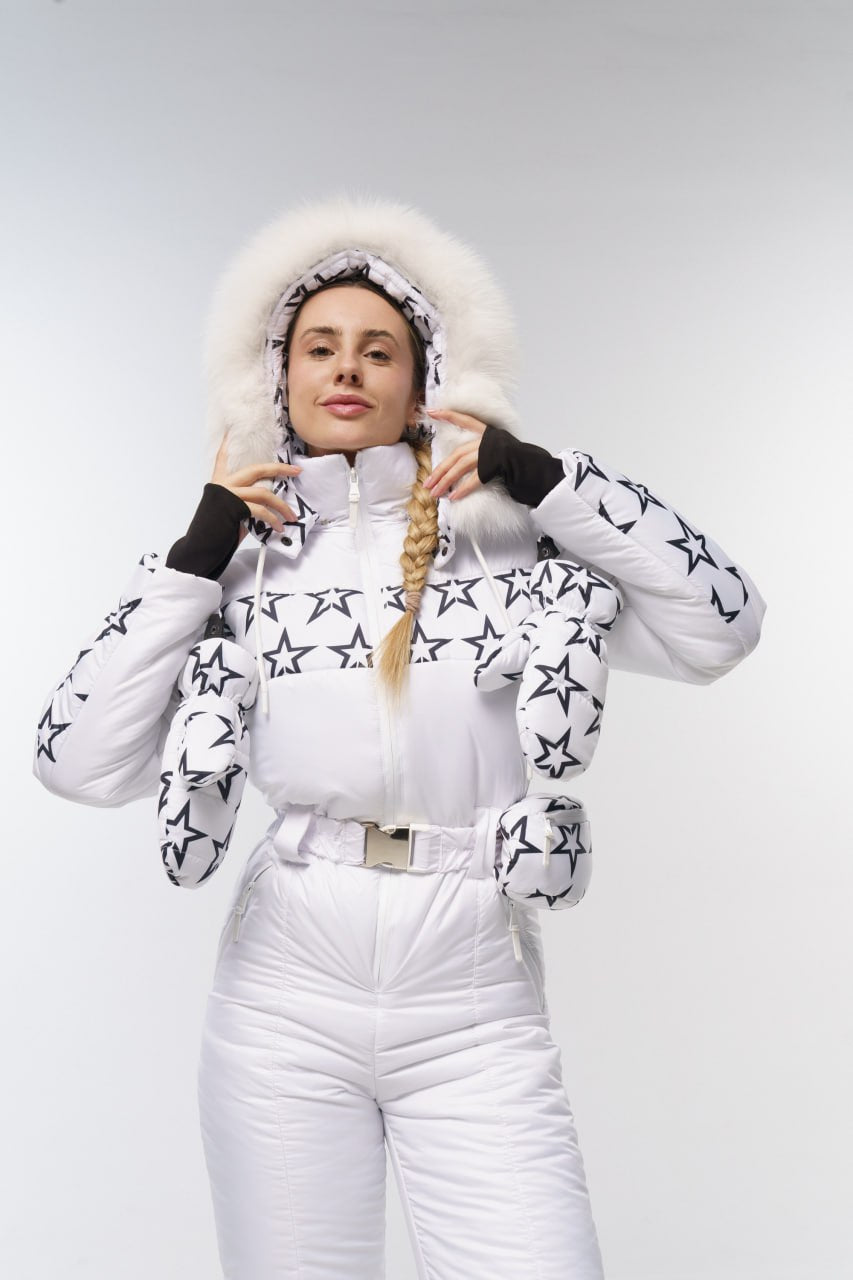 Person wearing a white puffer jacket with star patterns and white pants on a light gray background