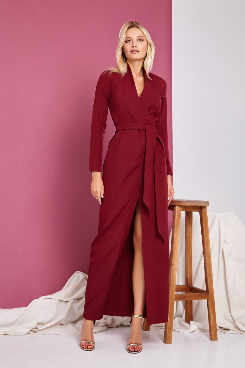 Woman wearing a red dress with a slit standing against a pink and white background