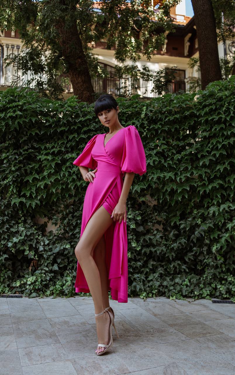 Woman in a bright pink dress standing in front of greenery