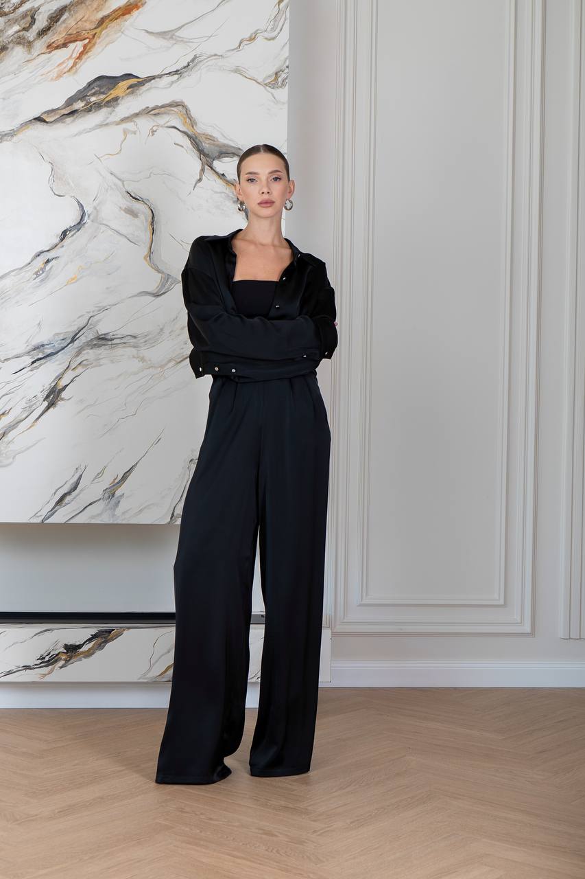 Person wearing a black outfit in a room with marble wall and wooden floor