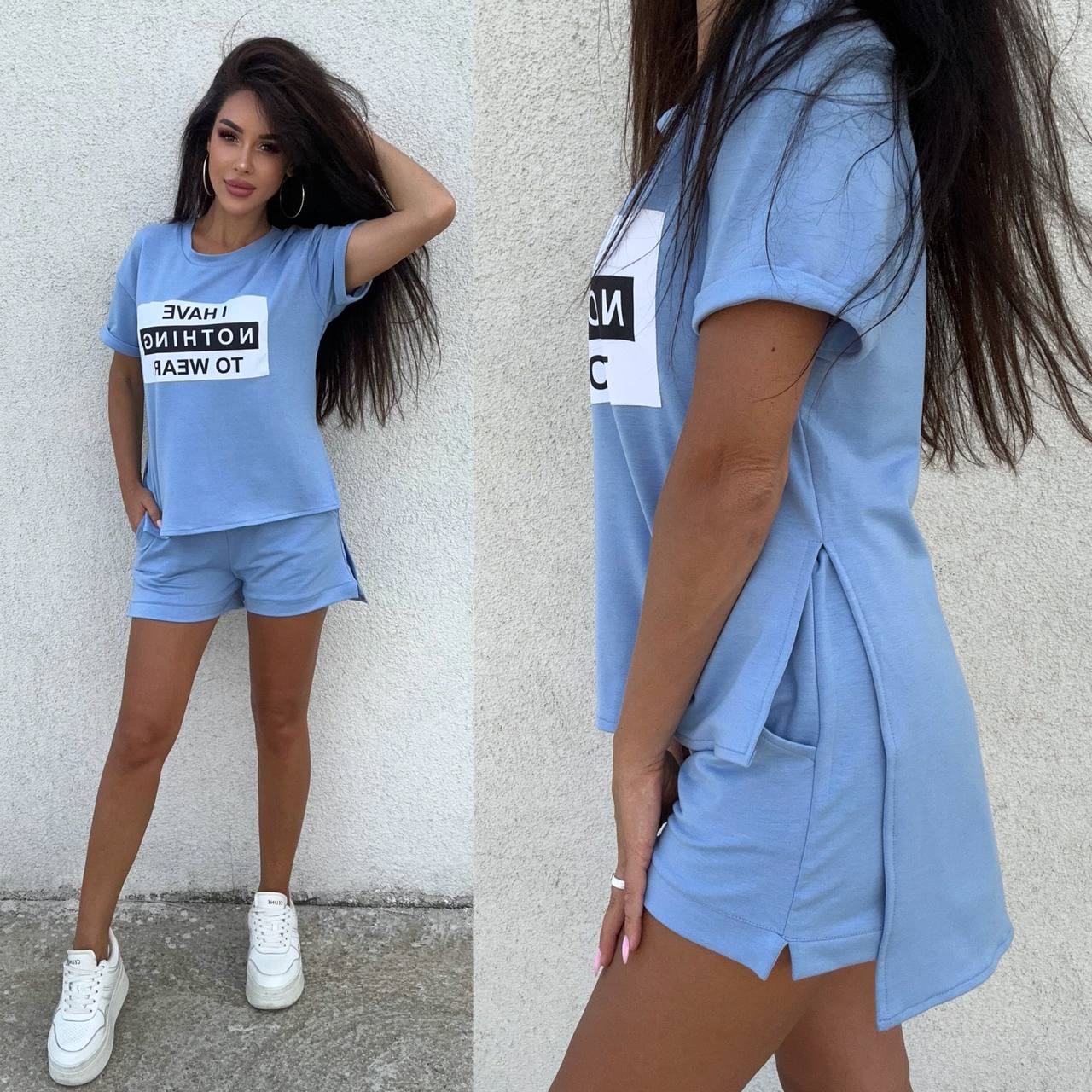 Woman wearing a light blue outfit with text on the shirt against a white wall.